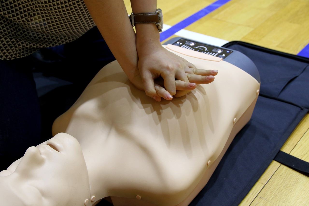 A person trains in CPR on a dummy. 